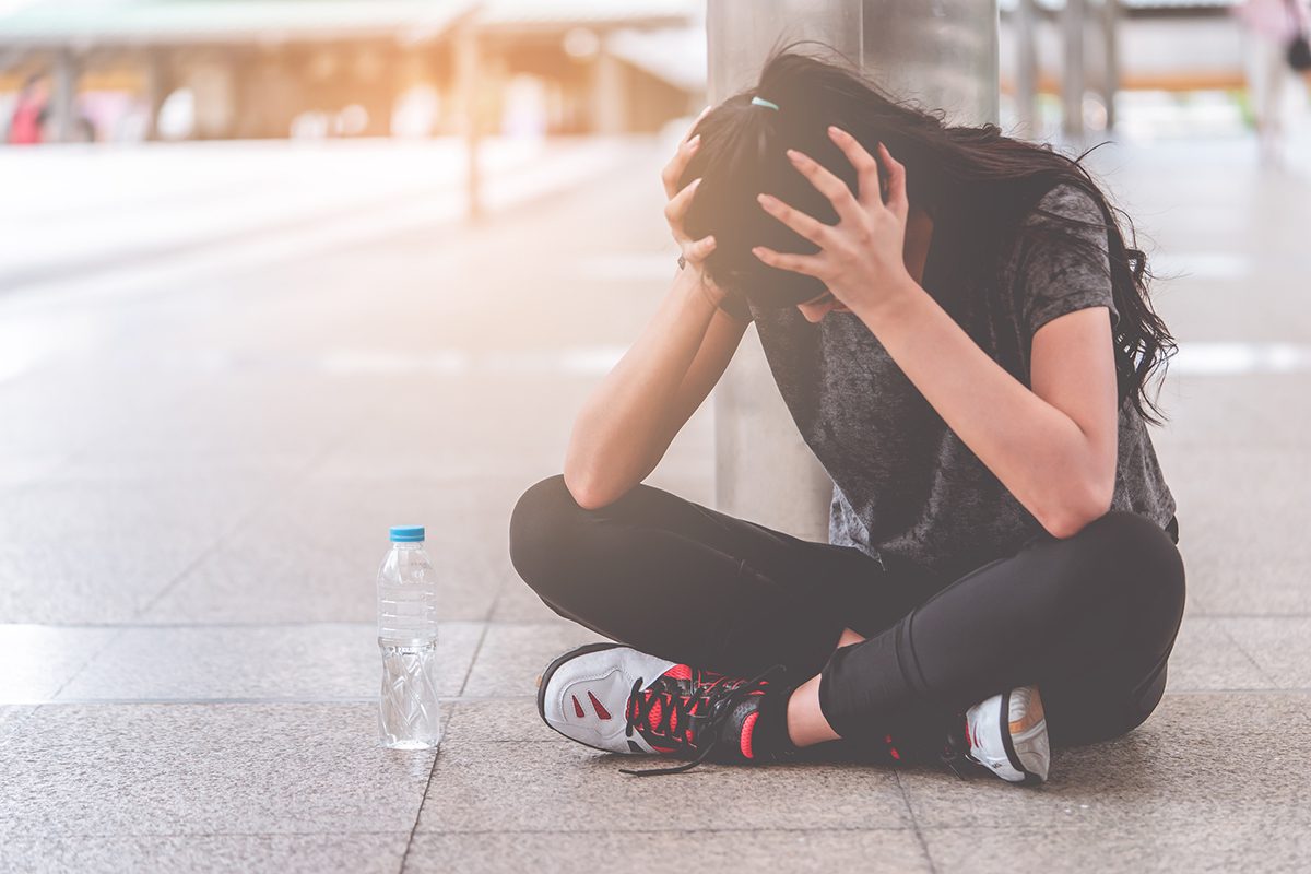 Woman with hand on her head getting headache after physical activity Woman with hand on her head getting headache after physical activity